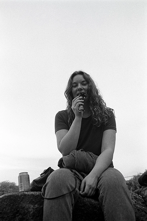 Black and white anlaog photograph of a woman eating a chocolate bar